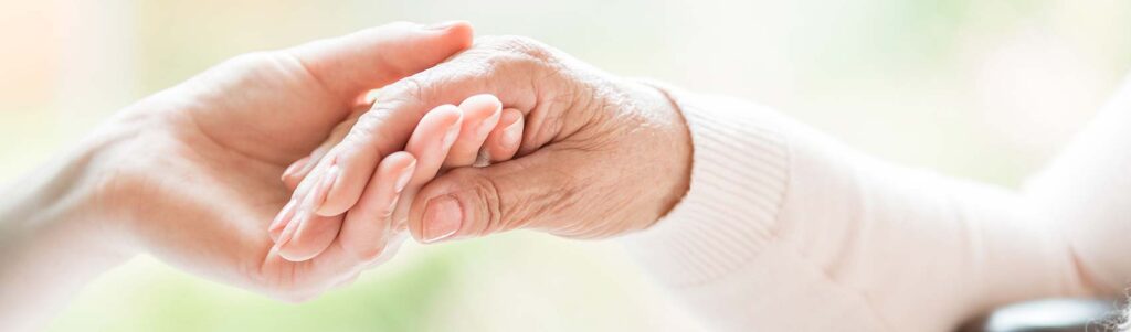 Close-up of tender gesture between two generations. Young woman holding hands with a senior lady.