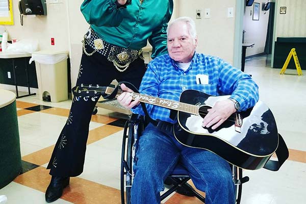 Senior man playing guitar in wheelchair.
